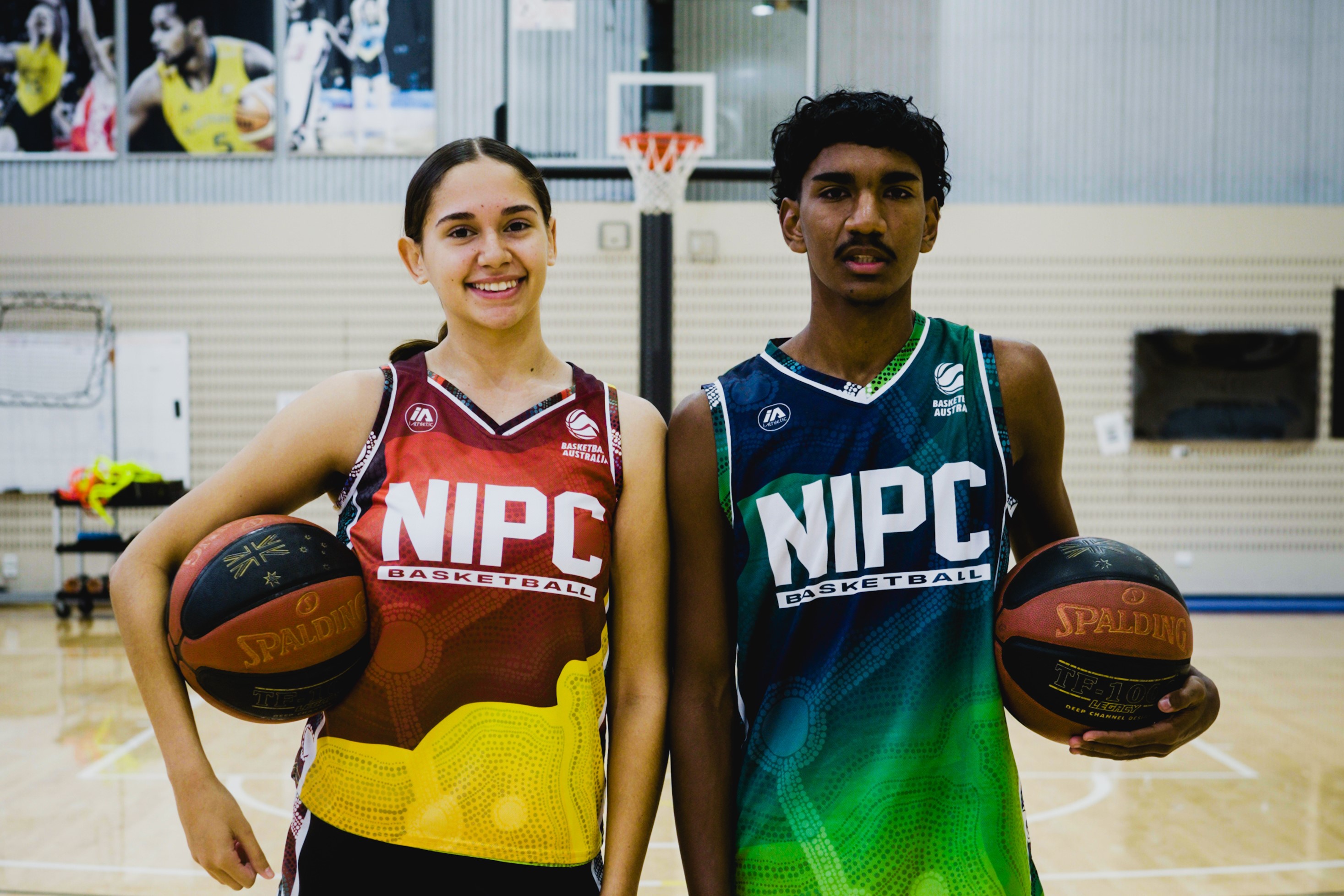 Two basketballers holding basketballs wearing NIPC singlets at the AIS.