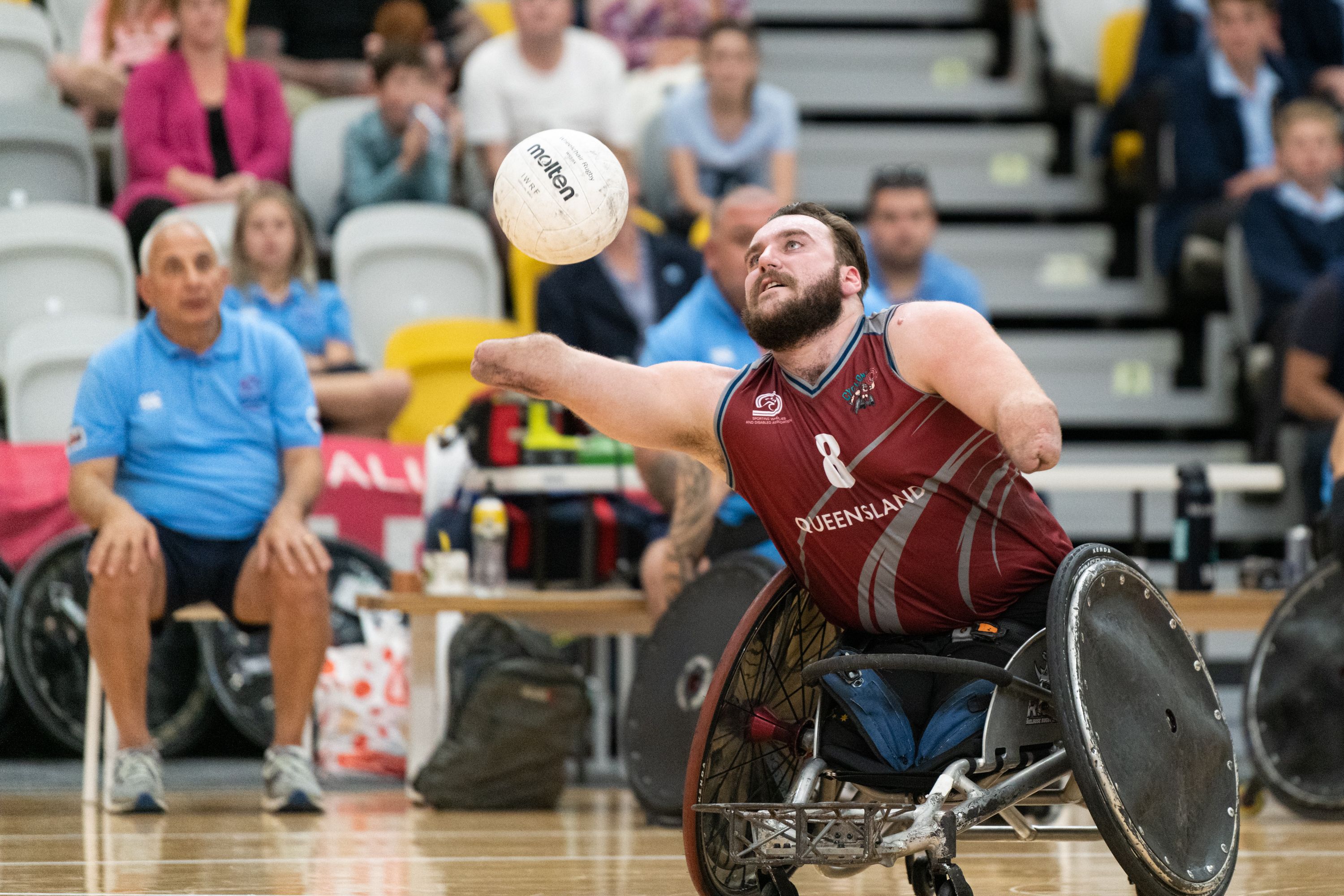 Wheelchair rugby player competes for the ball while the crowd watches on