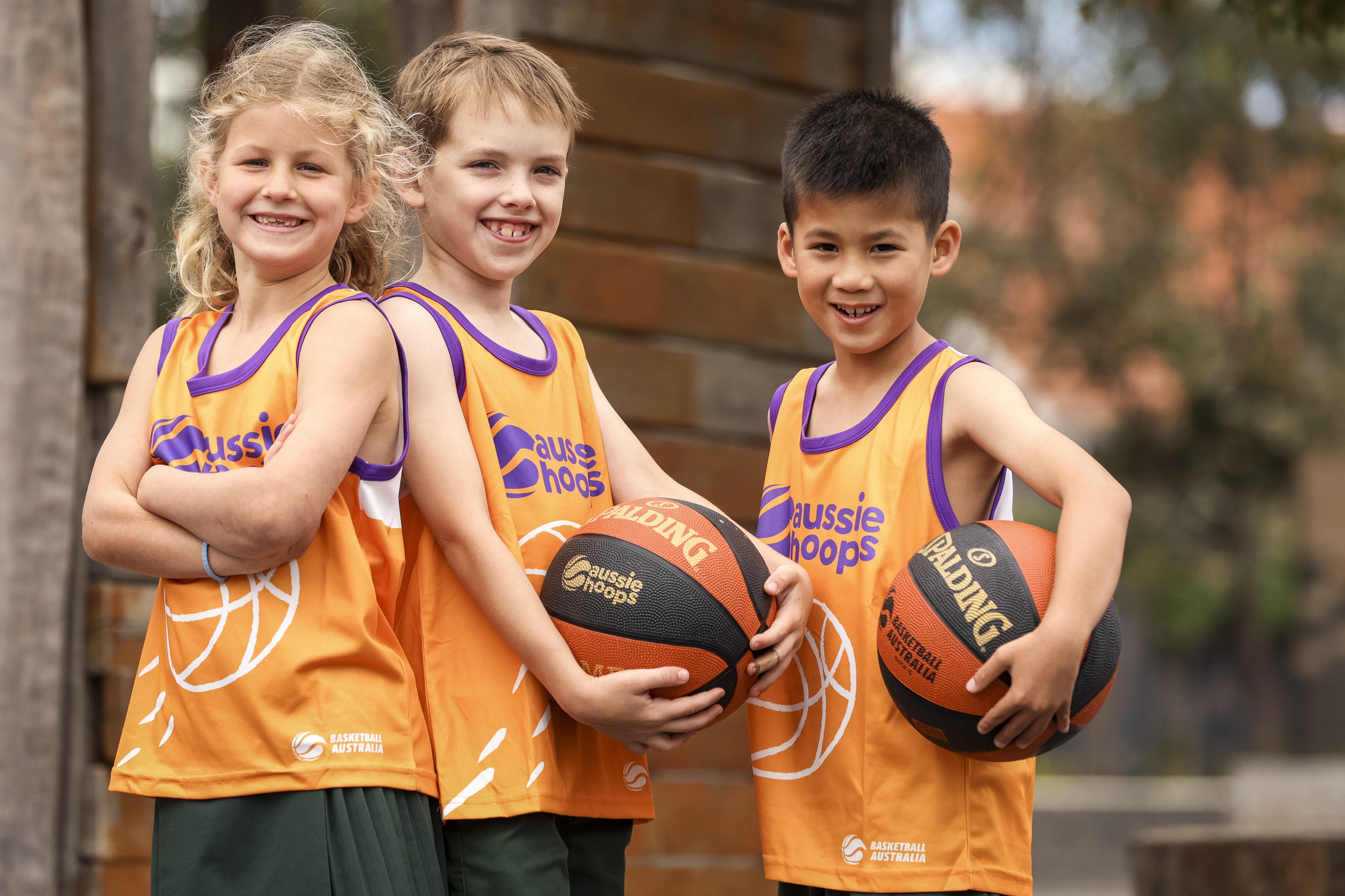 Three children in Aussie Hoops singlests holding a basketball