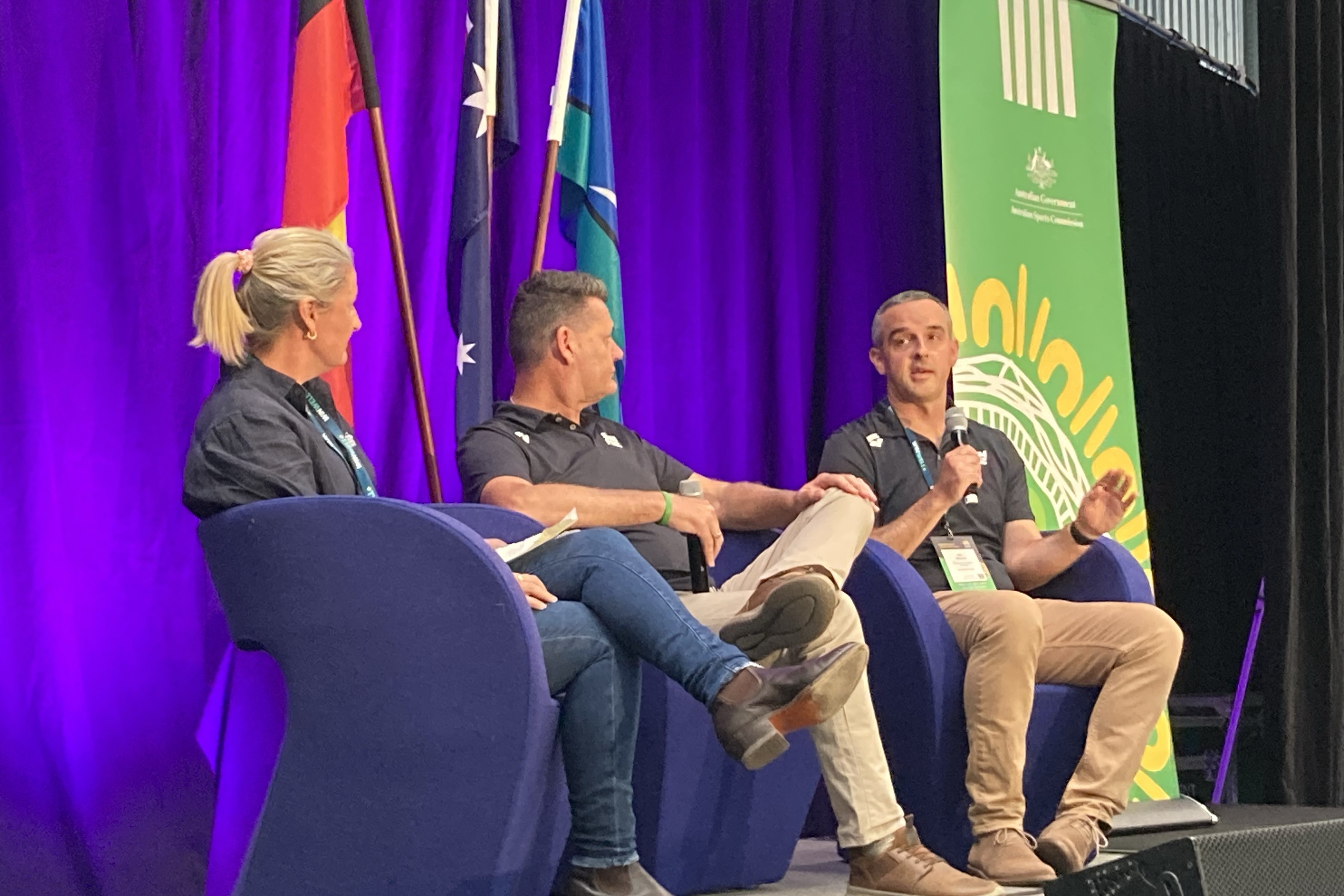 Three Swimming Australia leaders sitting on stage discussing how they leverage data and tech for performance outcomes. The speakers were Jess Corones, General Manager of Performance Support and Olympic Campaign, Rohan Taylor, National Head Coach and Ian Morrow, General Manager of Performance Insights & Technology.