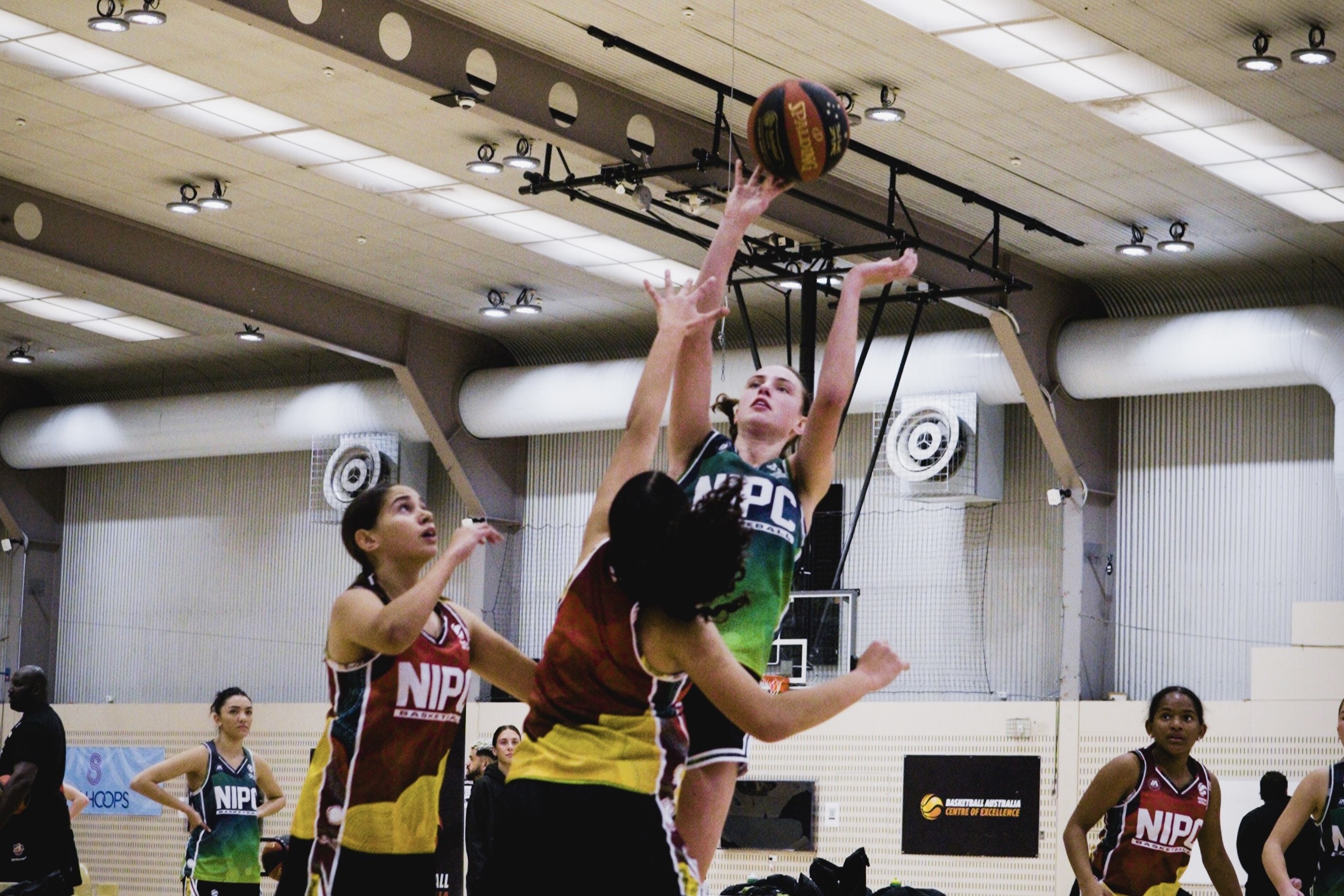 One player shooting and two defending during a game at the NIPC camp.