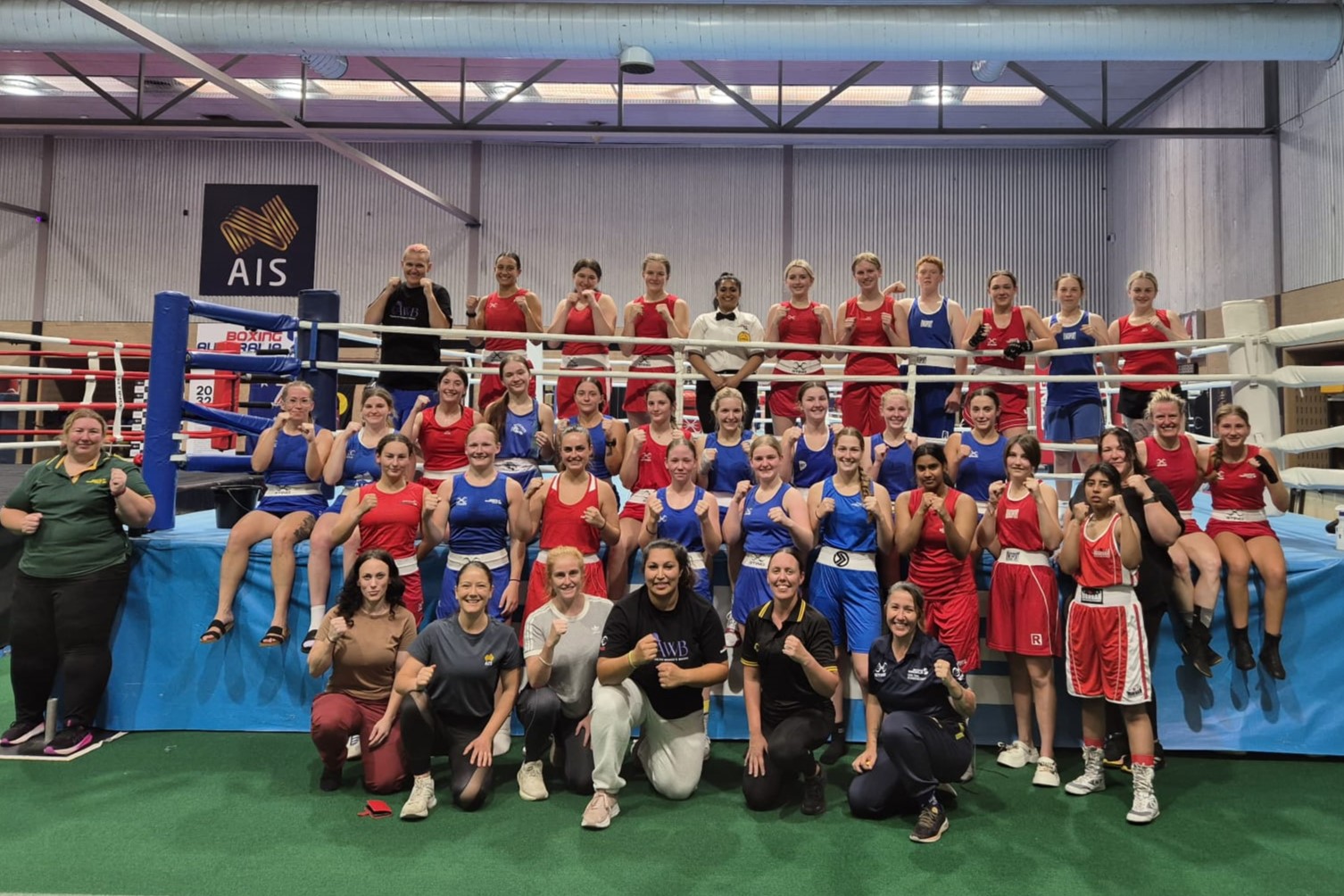 The 41 attendees stand around a boxing ring for a camp photo at the AIS.